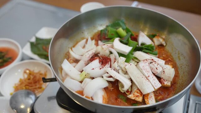 Sizzling pot holds tender squid and tofu. Fresh greens add color to the simmering broth. Red spice dusts the dish, inviting taste. Warm, comforting meal ready for sharing. Perfect for food blogs