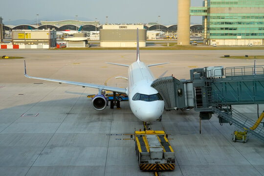Commercial airplane is connected via a hose for boarding passengers, and ready for tow push back truck preparing for the flight.