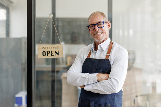 Senior business owner smiling with open sign in shop