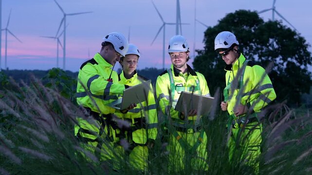 Team of engineers collaborating in wind farm project at dusk technical meeting outdoor setting professional environment
