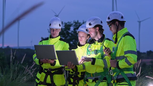 Nighttime team collaboration wind farm site technical review outdoor close-up engineering innovation