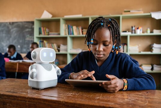 African girl using a digital tablet to program an educational robot in a classroom for stem learning, primary school education and technology literacy storytelling