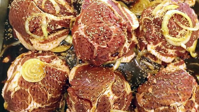 양념 소고기 불고기 한식 요리 식재료 서울: 대한민국 서울의 식당 혹은 가정에서 준비된 양념 육류의 모습입니다. 신선한 고기에 양파와 참깨가 고명으로 올라간 먹음직스러운 비주얼을 클로즈업하여 담아냈으며, 한국 전통 음식 문화와 외식 산업, 요리 레시피 등을 상징하는 실내 영상입니다.