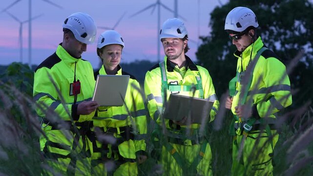 Team of engineers collaborating on renewable energy project wind farm meeting outdoor close-up innovation