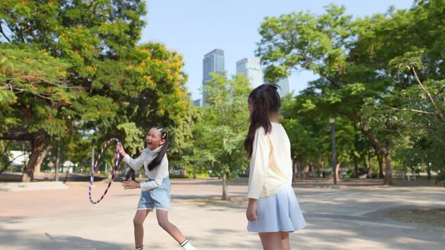 Two Young Asian Girls Playing with Hula Hoops in Bangkok Park