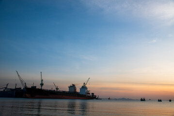 Obraz premium Logistics seascape shipping portal. Logistic shipping quay boat Engineering crane depot at logistic export terminal control. . Logistic shipping quay boat in twilight sky night Engineering crane