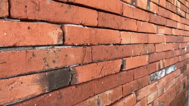 Weathered brick wall shows aged, rustic charm. Mortar lines reveal time's gentle wear. Red bricks stand strong, textured and worn. Ideal for vintage, industrial, or architectural themes. close up view