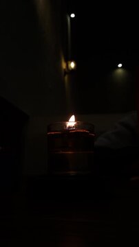 Close-up of a flickering aromatic candle on a dinner table in a luxury fine-dining restaurant. The warm flame moves gently in the breeze, creating a romantic and intimate atmosphere for a candle light