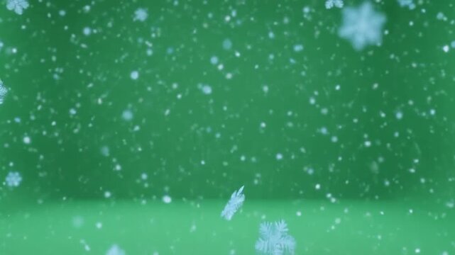 Soft white snowflakes falling gently against a solid green background