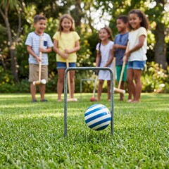 Obraz premium A striped croquet ball passing through a metal wicket on a manicured lawn, with children holding mallets in the blurred background, highlighting youthful recreation 1:1 ratio.