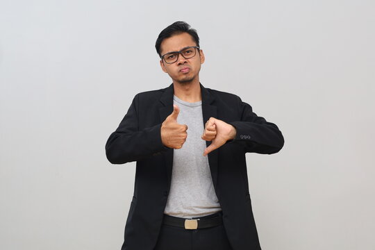 The young male businessman gave a thumbs up and down, showing an expression of disapproval and approval, an inner conflict.
