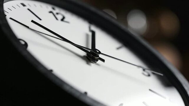 Close-up view of a clock shows exact time in a dark room