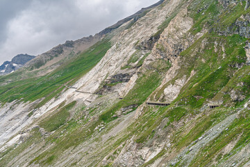 Obraz premium Grossglockner High Alpine Road tunnels are carved into the steep mountain slope in Austria, Europe. This scenic route offers stunning views and is a popular tourist destination.