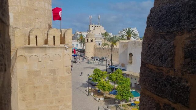 View from the fortress walls over the central square of the historic Medina of Sousse, Tunisia, a UNESCO World Heritage site, with the Tunisian flag swaying in the wind on a sunny day