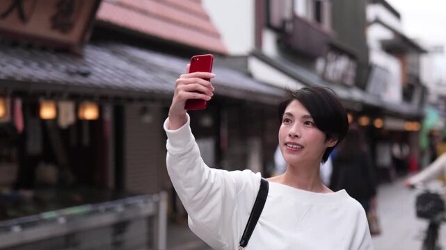 観光地でスマートフォンで写真を撮る女性