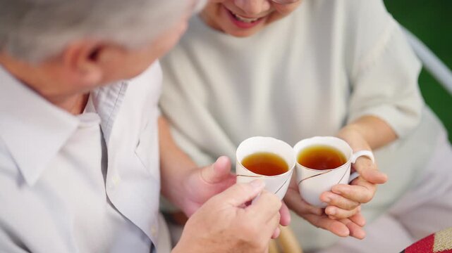Happy Asian family senior couple enjoy afternoon tea together in the garden, elderly husband and wife relaxing outdoors during retirement lifestyle, healthy aging older spending quality time at home