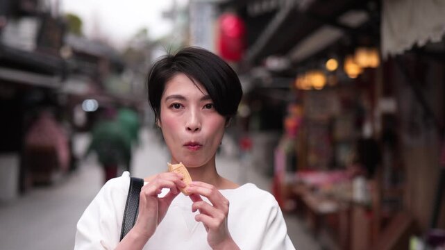 観光地で和菓子を食べる女性のクローズアップ