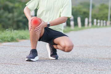 Fototapeta premium Young adult male runner with knee pain from ACL injury or patellofemoral syndrome. Man having joint ache, ligament tear or patellar tendinitis during running. Sports medical and healthcare concept