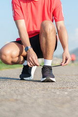 Fototapeta premium Young Asian man tying running shoes in the park. Female runner getting ready for jogging and exercise on the road. Fitness, wellness and outdoor sport concept in morning