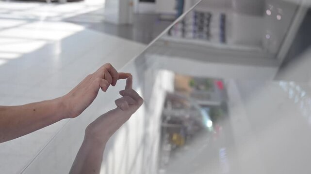 A faceless woman uses a touchscreen information stand. 