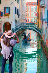 Venetian gondolier punting gondola through green canal waters of Venice Italy © muratart