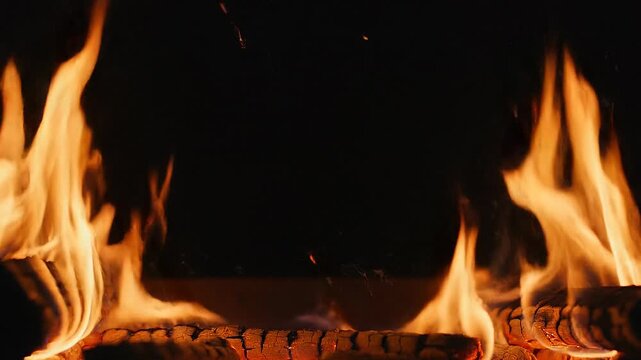 Animated fire frame on black background concept. Close up of bright orange flames burning wooden logs in a dark background warm fire