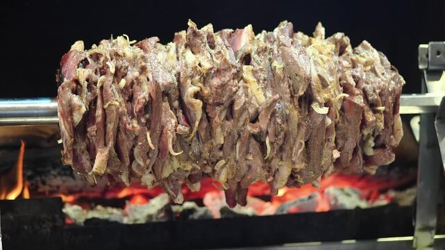 Cooking meat on a spit over hot coals in an open fire