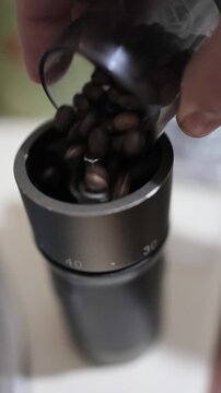 Pouring coffee beans into the hand grinder