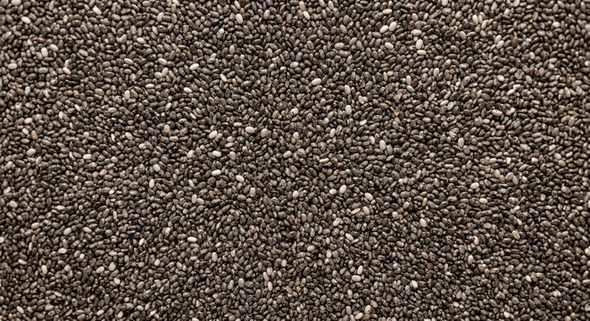 Overhead view of a dense, uniform scattering of tiny black chia seeds creating a textured dark background with subtle speckles of white and gray