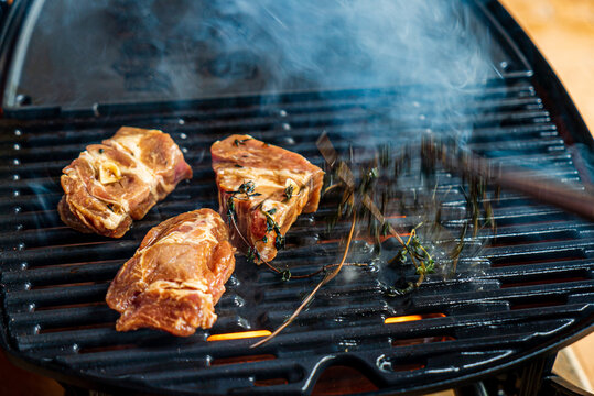 Grilling marinated meat with aromatic herbs on a sunny afternoon at a backyard barbecue