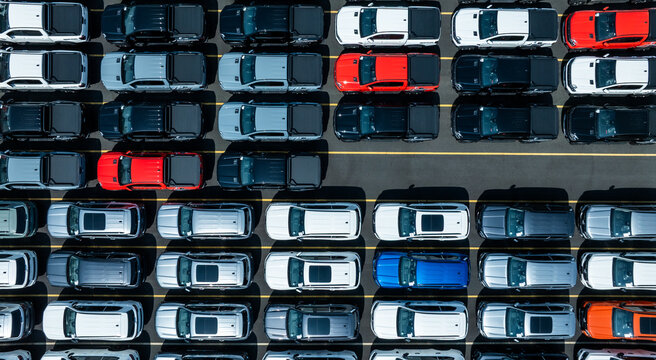 Aerial drone view of thousands of new cars parked at port for global export.