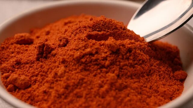 Cinematic Macro Shot of Red Chili Powder in Spoon from Bowl on Table &ndash; Angled Top View with Soft Blurred Background, 4K Food Stock Footage