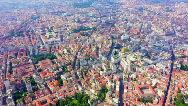 Milan, Italy. The Duomo di Milano and Galleria Vittorio Emanuele II, a sweeping Drone footage over terracotta rooftops and the cathedral's forest of white marble spires under soft daylight. Drone foo