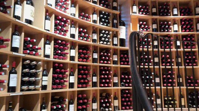 Curved Wooden Shelves Filled with Red Wine Bottles in Bordeaux Cellar