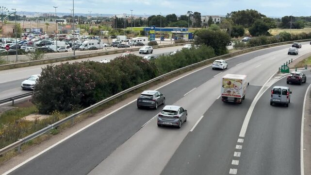 Palma, spain, may 7, 2026, cars and vans driving on a multi lane highway with moderate traffic flowing through a suburban area during the daytime
