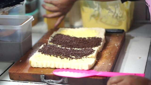 Toast seller's hand puts milk and sprinkles ceres on toast for his customer	