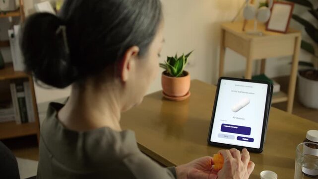 Senior woman holding smartphone with medication reminder and pills, highlighting digital health, medication management, and independent living. Reflects mHealth, routine, senior care, and wellbeing.