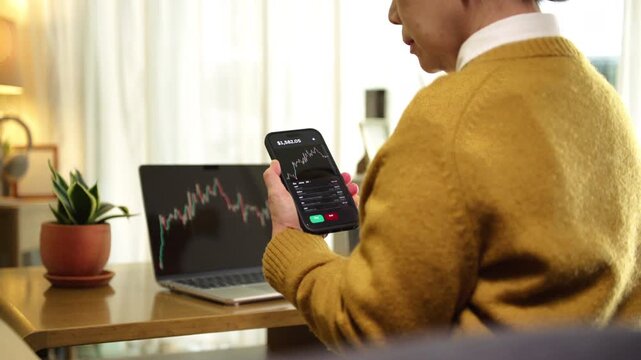Senior woman using laptop and smartphone to monitor stock market data, highlighting investing, financial independence, and retirement planning. Reflects online trading and smart money management.
