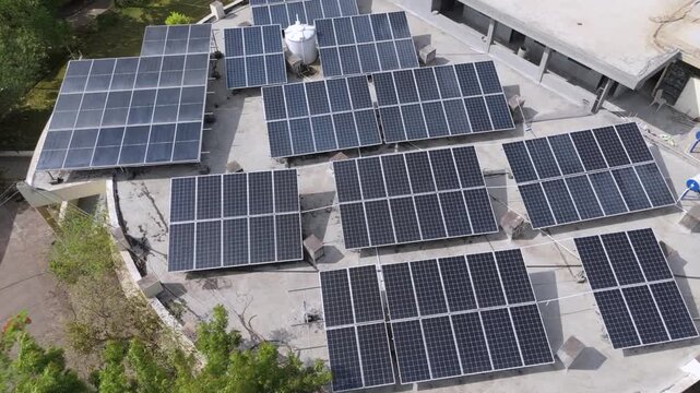 An aerial view of a modern rooftop solar power system installed on a large building. Multiple photovoltaic solar panels are arranged efficiently across the rooftop to generate clean, renewable energy.