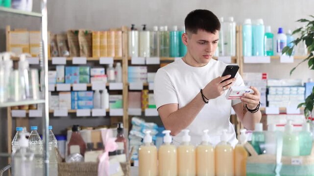 Attentive young guy client choosing box of paracetamol antipyretic pills, scan QR code on label, looking at composition of medicine in modern drug store