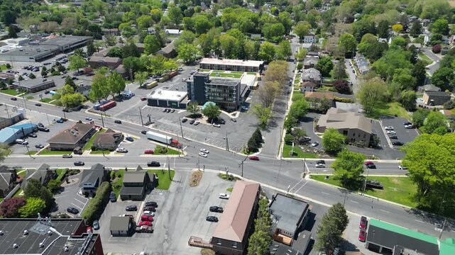 High angle drone footage capturing a complex five way road intersection with traffic flow and surrounding commercial retail buildings on a sunny day.