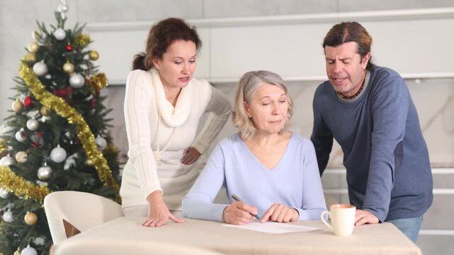 On Christmas Eve man and woman help elderly mother make will and fill out document correctly. Family advice, help and support