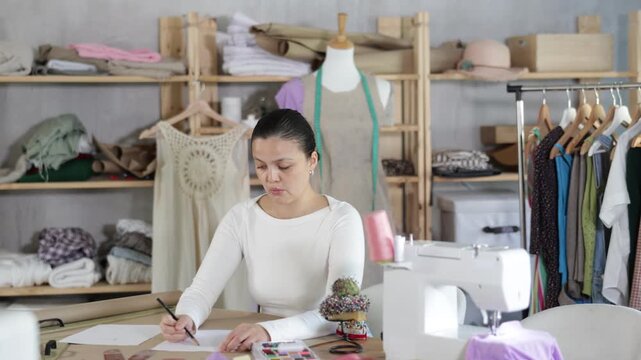 Asian fashion designer draws a sketch on paper. Process of creating a clothing collection according to an individual layout. High quality 4k footage