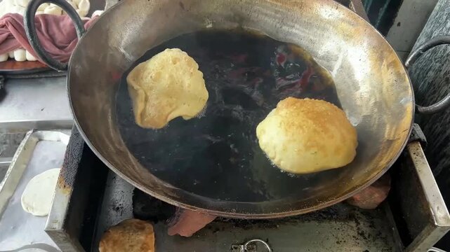 Dal puri being fried in a local shop in Kolkata; professional street food photography of live deep-frying action, traditional Bengali breakfast snacks, and popular roadside delicacies of India.