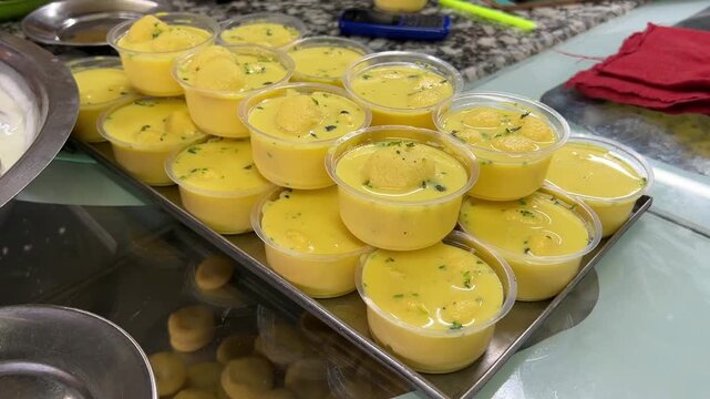 A vibrant display of traditional yellow-hued Bengali Rasmalai, featuring soft, spongy cottage cheese patties soaked in saffron-infused cardamom milk syrup, sold at a heritage sweet shop in Kolkata.