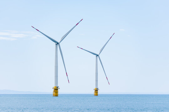 富山湾の青い海に広がる洋上風力発電と能登半島の遠景。クリーンなエネルギーと共生する新しい日本の風景。