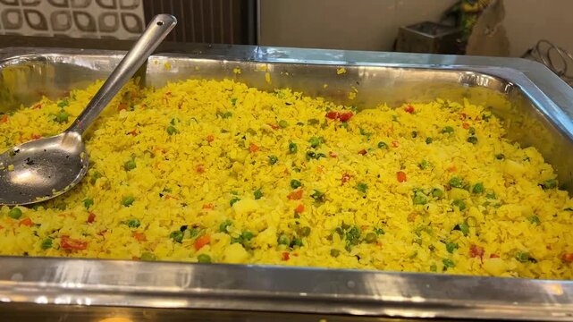 Light and fluffy Indore-style poha garnished with crispy sev and fresh pomegranate seeds, served beautifully at a live breakfast buffet station during an Indian wedding.
