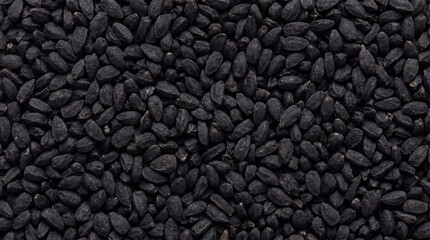 Fototapeta premium An intense, high-angle view of a dense scattering of small, black nigella seeds, also known as kalonji, highlighting their unique shape and dark, matte finish