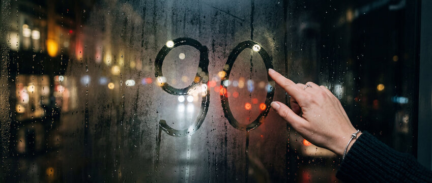 Hand drawing number ninety on steamy window at night