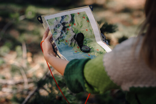 Person holding map and compass navigating outdoors
